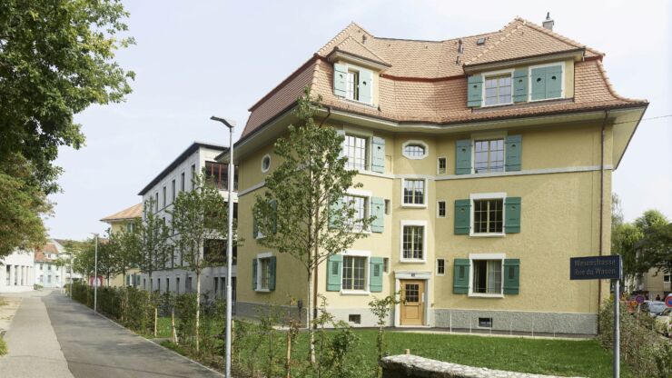 Platz 3: Siedlung Wasenstrasse 34-46. Das Foto zeigt ein renoviertes Gebäude mit gelb gestrichener Fassade und grünen Fensterläden.
