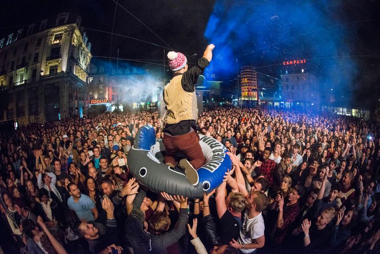 Der Musiker Cee-Roo wird nachts an einem Konzert auf dem Zentralplatz in einem blauen Schwimmring über die Menschenmenge getragen.