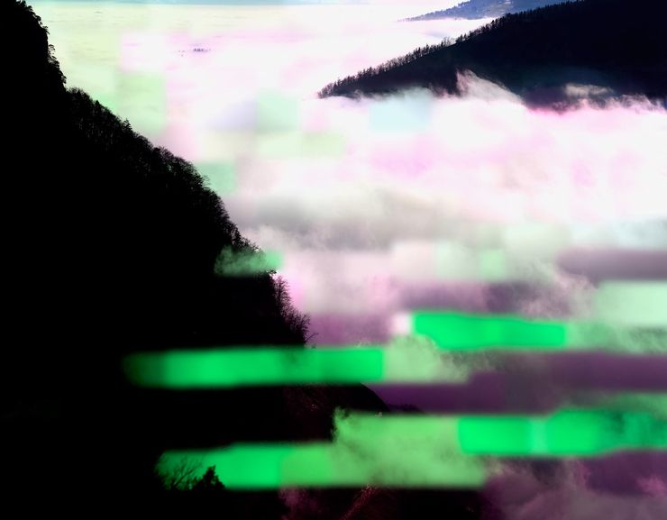 Eine Fotografie zeigt mit Nebel gefüllte Täler, die von dunklen Waldflächen umgeben sind. Speziell an dem Bild sind die unechten, grünen und violetten Bildstreifen. 