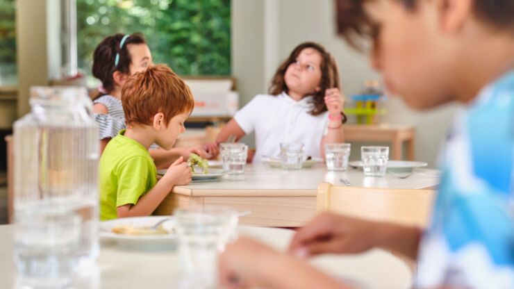 Kinder sitzen gemeinsam an einem Tisch und essen zu Mittag.