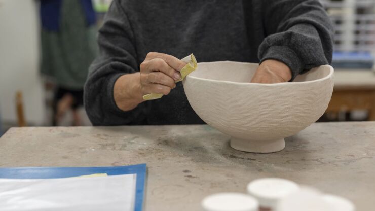 Eine Teilnehmerin des Keramikateliers schleift an einer Tonschüssel.
