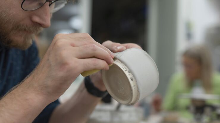 Ein Teilnehmer des Keramikateliers schleift an einer Tonschale.