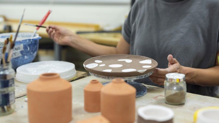 Eine Teilnehmerin des Keramikateliers glasiert einen Teller.
