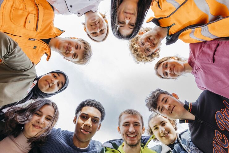 11 apprenties et apprentis de la Ville de Bienne de différentes professions se tiennent en cercle. On voit leur visage car la photo est prise depuis l'intérieur du cercle.  