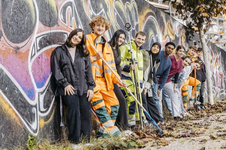 11 Lernende der Stadt Biel aus verschiedenen Berufen stehen vor einer Graffiti-Palisade.