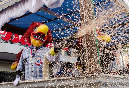 Un carnavalier masqué disperse des confettis à partir d'un char de cortège.