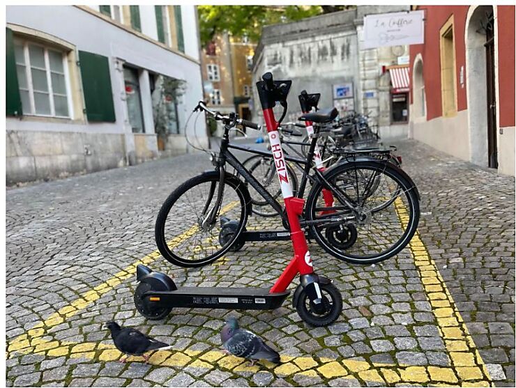 Sicht auf einen Parkplatz, der für Zweiräder vorgesehen ist. Ein Trottinett steht im Vordergrund vor Fahrrädern in der Bieler Altstadt. 