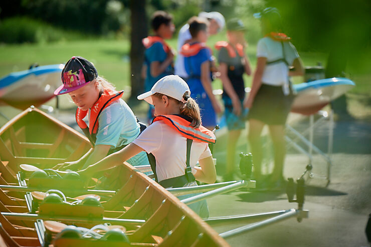 Mehrere Kinder bereiten auf dem Ufer ein Boot vor.